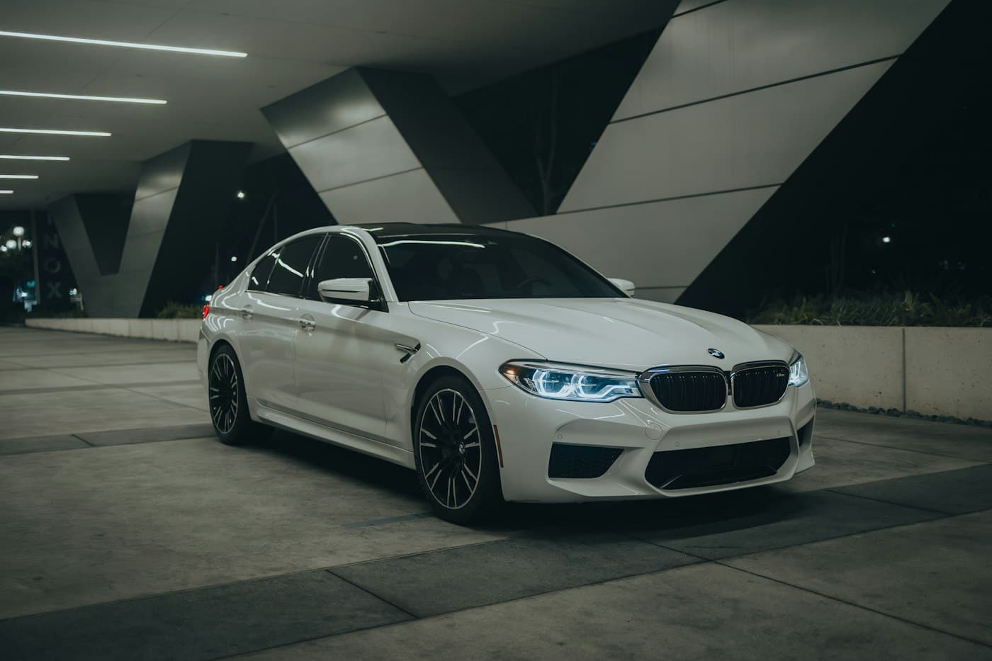 White BMW 5 Series sedan in a parking garage