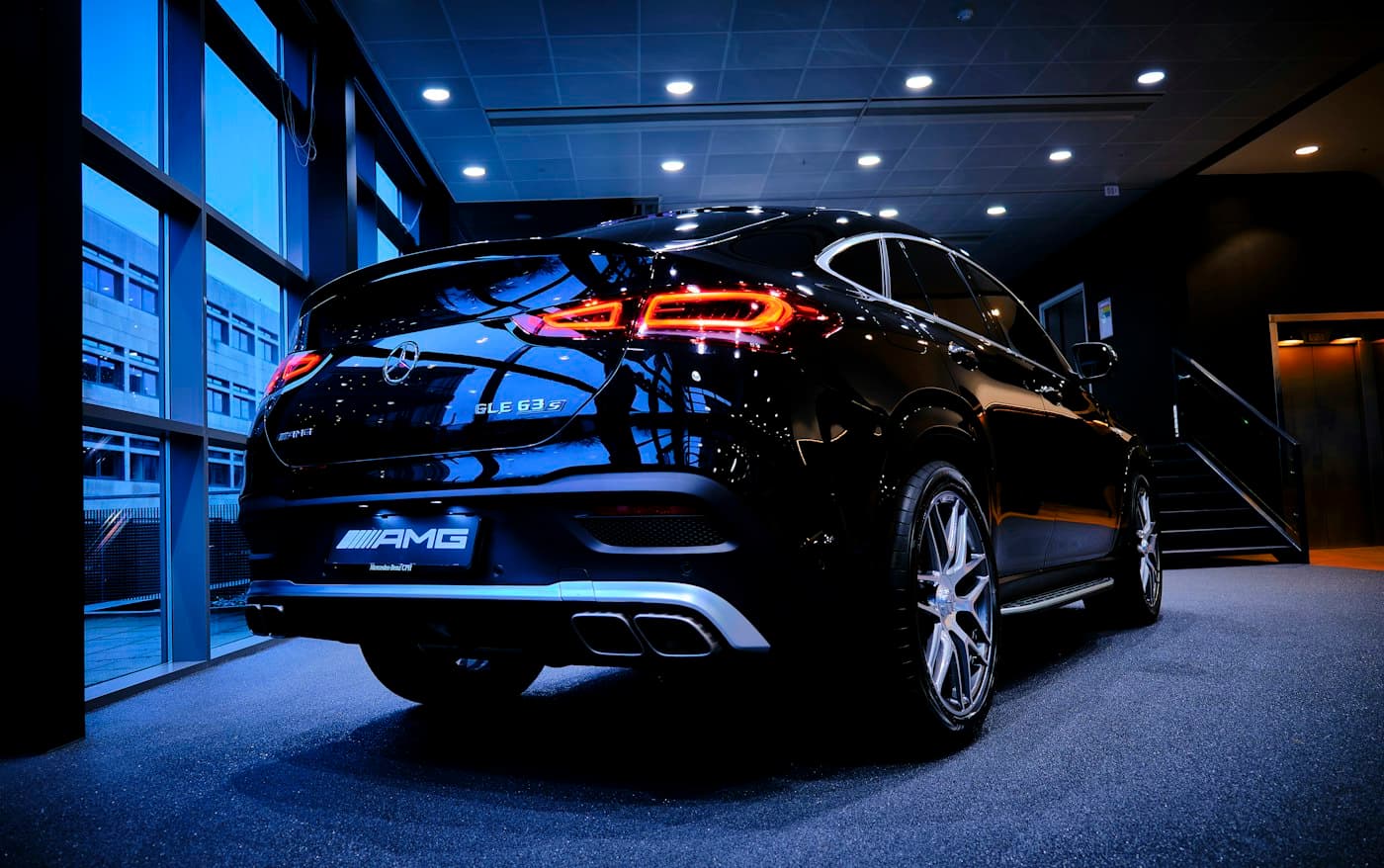 Black Mercedes-AMG GLE 63 S Coupé rear view in a glass-walled showroom